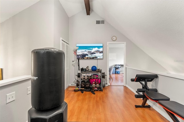 workout area featuring hardwood / wood-style flooring, vaulted ceiling, and a textured ceiling