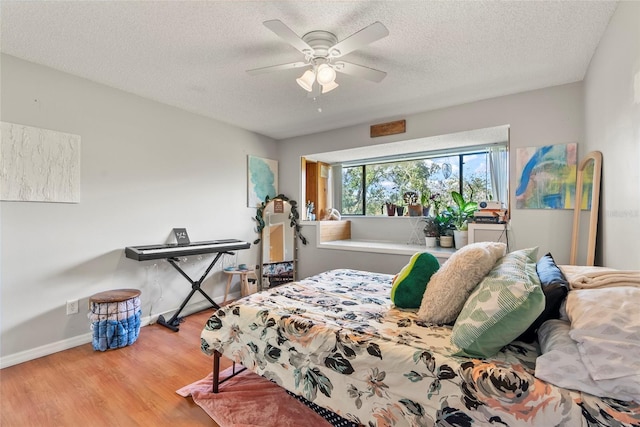 bedroom with ceiling fan, wood-type flooring, and a textured ceiling