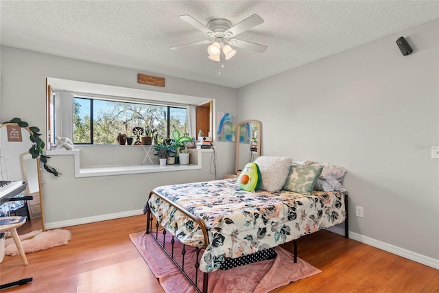 bedroom featuring ceiling fan, a textured ceiling, and light hardwood / wood-style floors