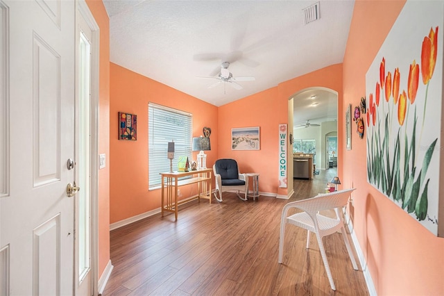 living area featuring a textured ceiling, wood-type flooring, ceiling fan, and vaulted ceiling