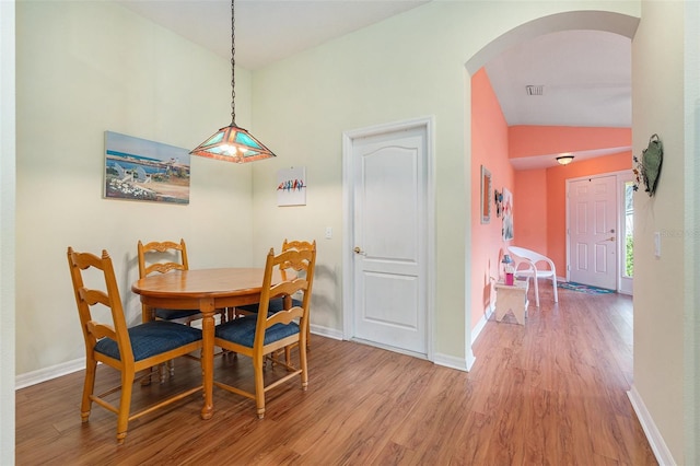 dining space with wood-type flooring and vaulted ceiling