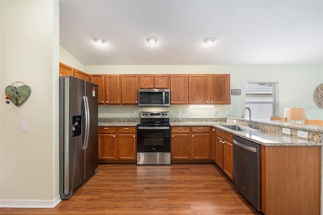 kitchen featuring light stone counters, stainless steel appliances, dark wood-type flooring, and sink