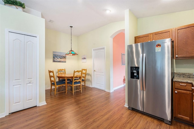 kitchen featuring stainless steel refrigerator with ice dispenser, vaulted ceiling, pendant lighting, and dark hardwood / wood-style flooring