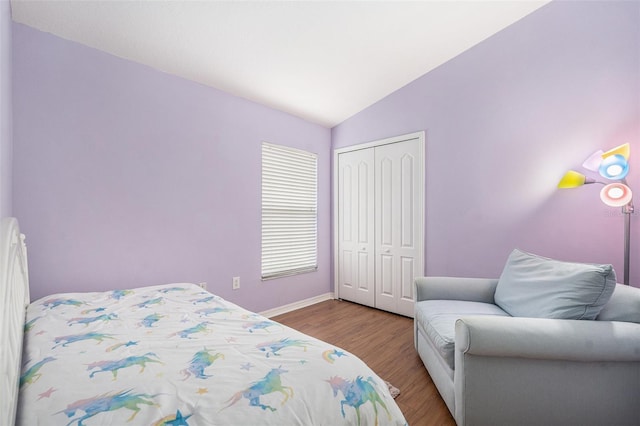 bedroom with vaulted ceiling, light wood-type flooring, and a closet