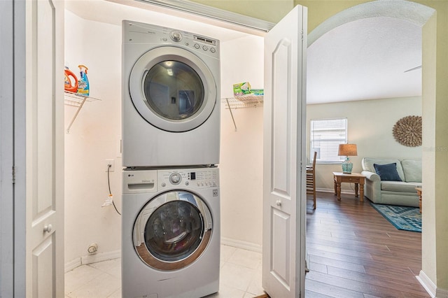 clothes washing area with light hardwood / wood-style floors and stacked washer and clothes dryer