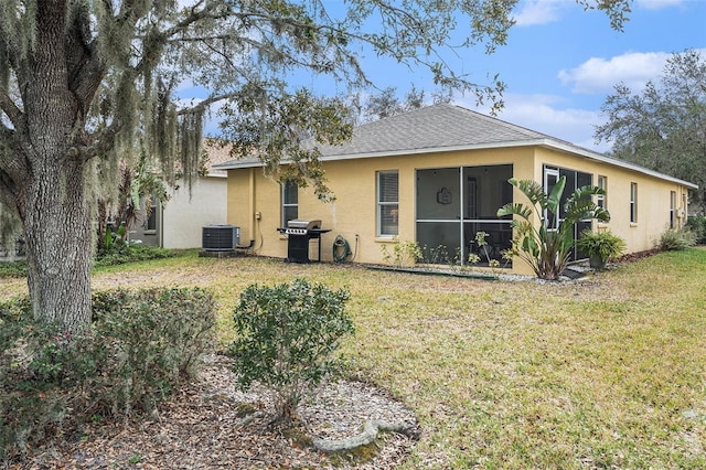 back of property featuring a sunroom, a yard, and central AC