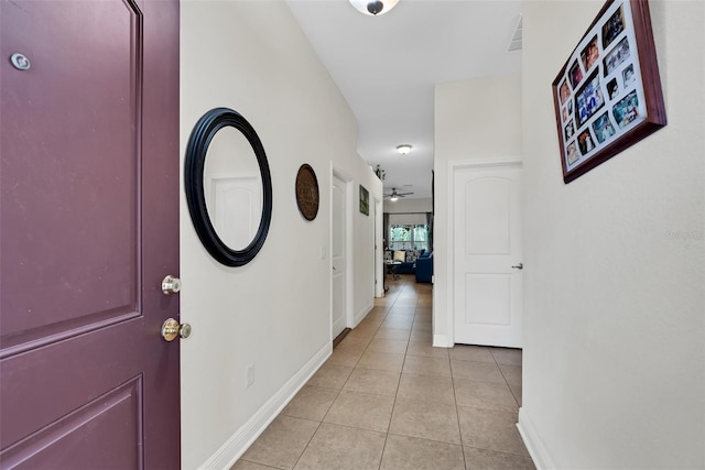 hallway featuring baseboards and light tile patterned flooring