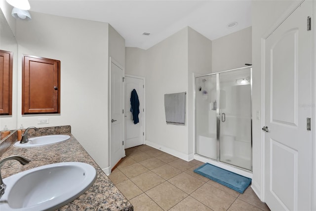 bathroom featuring a stall shower, double vanity, a sink, and tile patterned floors