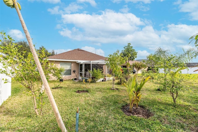 rear view of house featuring a lanai, a yard, and stucco siding