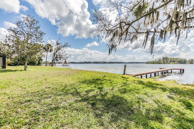 view of dock with a yard and a water view