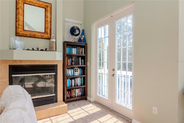 doorway featuring a tile fireplace, carpet, and french doors