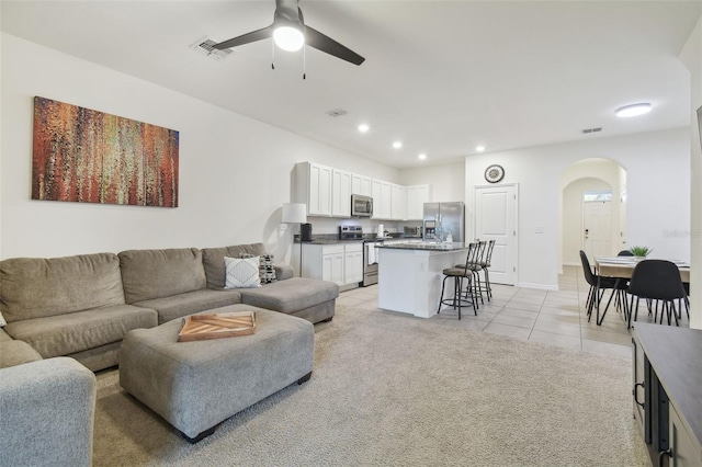 living room featuring arched walkways, a ceiling fan, light tile patterned flooring, recessed lighting, and baseboards