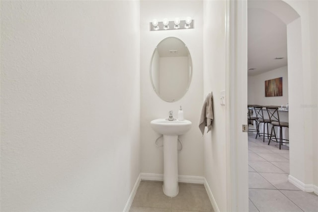 bathroom featuring tile patterned flooring, baseboards, and a sink