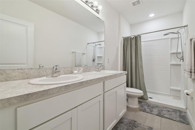bathroom with a shower stall, tile patterned floors, double vanity, and toilet