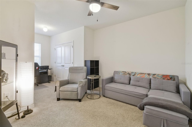 carpeted living room with a ceiling fan and a desk