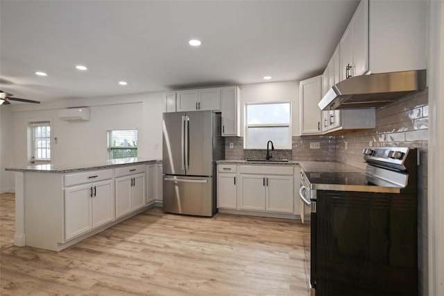 kitchen with sink, white cabinetry, a wall mounted AC, appliances with stainless steel finishes, and kitchen peninsula