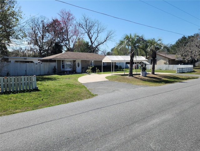 view of front facade featuring a front lawn, fence, driveway, and a carport