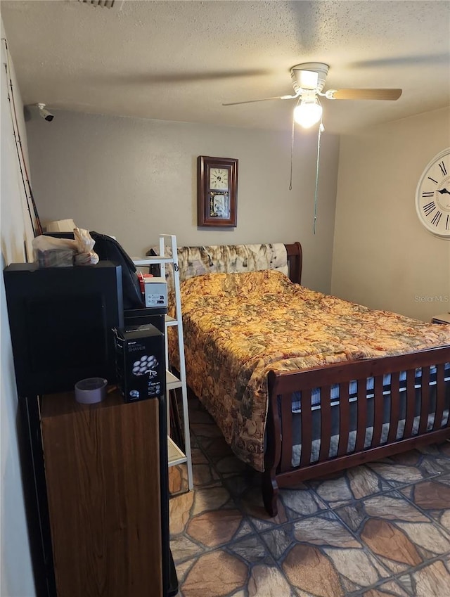 bedroom with ceiling fan and a textured ceiling