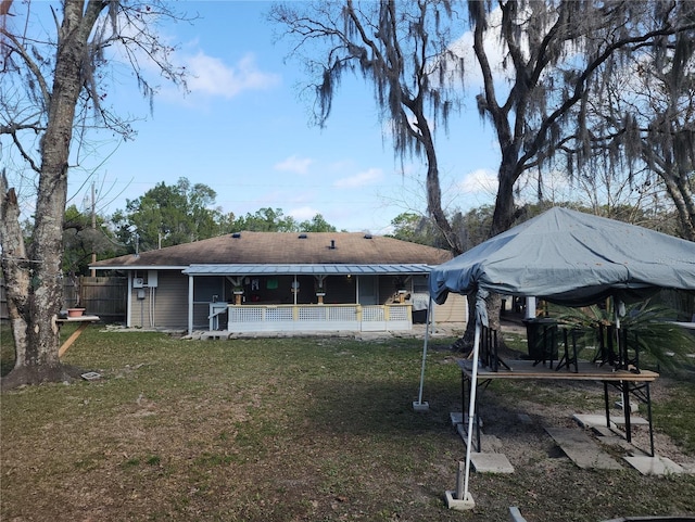 rear view of property with a trampoline and a yard