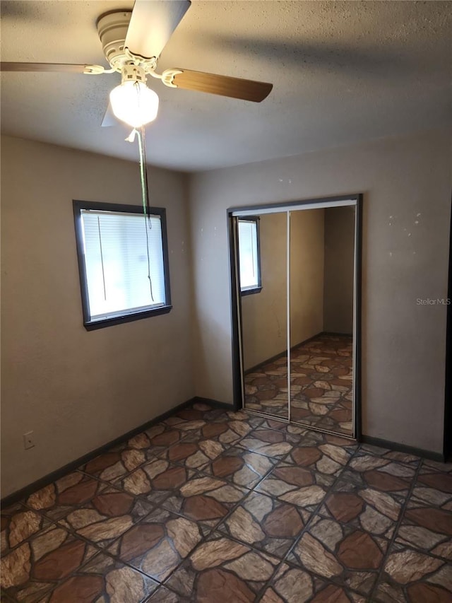 6328 W Park Dr, Homosassa, FL 34446 - unfurnished bedroom with a textured ceiling, a closet, a ceiling fan, and stone finish flooring