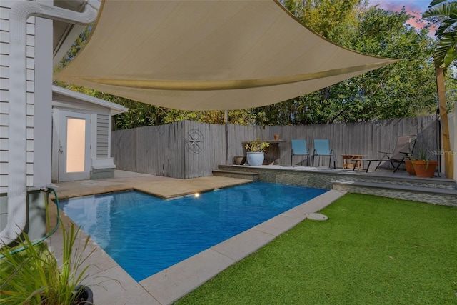 pool at dusk featuring a yard and a patio area