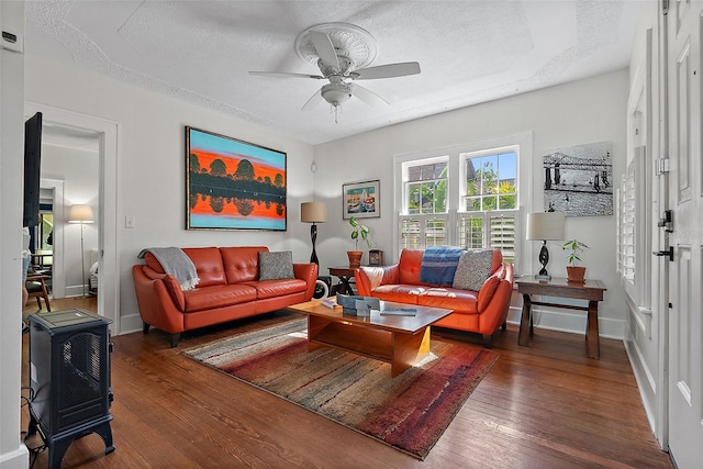 living room featuring dark wood-type flooring, ceiling fan, and a textured ceiling