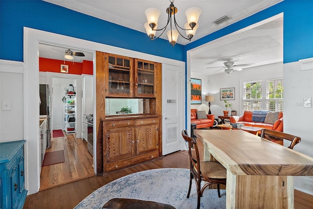 dining room with ceiling fan with notable chandelier and dark hardwood / wood-style flooring