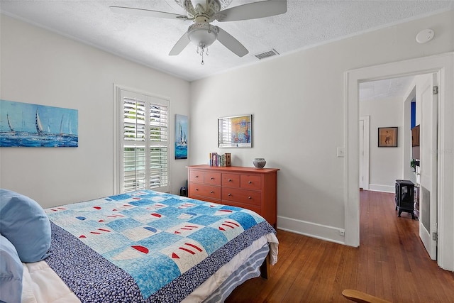 bedroom with ceiling fan, dark wood-type flooring, and a textured ceiling