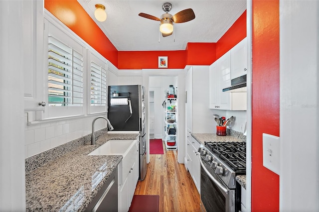 kitchen featuring light stone counters, white cabinetry, tasteful backsplash, light wood-type flooring, and stainless steel appliances