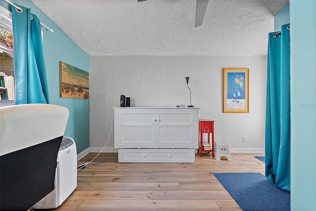 bedroom featuring ceiling fan, light hardwood / wood-style floors, and a textured ceiling