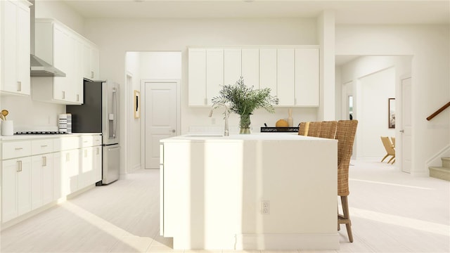 kitchen with stovetop, an island with sink, and white cabinets