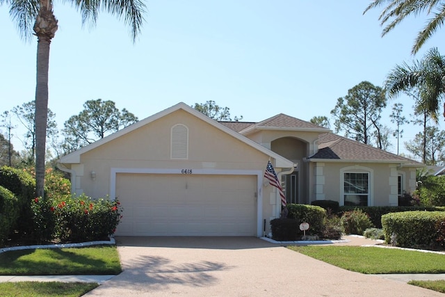 ranch-style home featuring a garage, roof with shingles, concrete driveway, and stucco siding