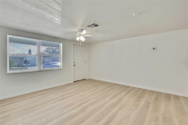 empty room with ceiling fan, light hardwood / wood-style floors, and a textured ceiling