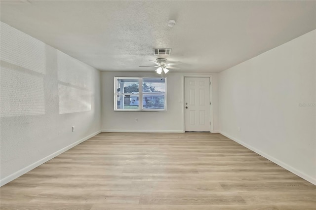 empty room with ceiling fan, light hardwood / wood-style flooring, and a textured ceiling