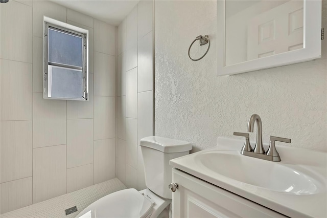 bathroom featuring vanity, toilet, and tiled shower