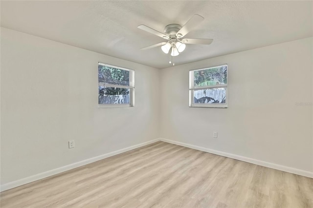 empty room with ceiling fan, a textured ceiling, and light wood-type flooring