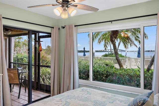 bedroom featuring ceiling fan, multiple windows, and a water view