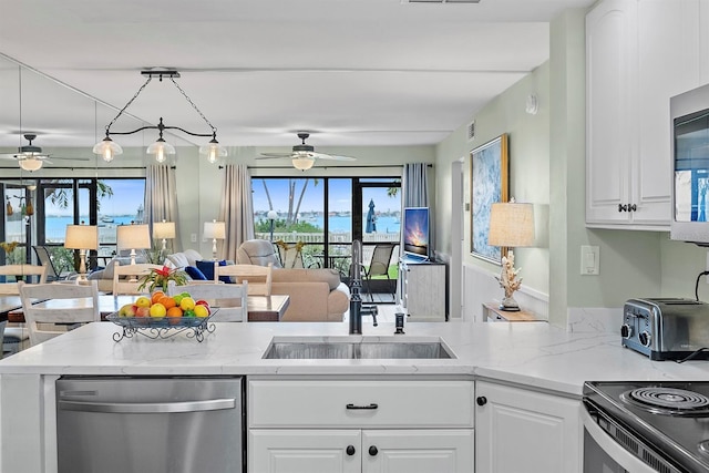 kitchen with white cabinets, appliances with stainless steel finishes, open floor plan, and light stone counters