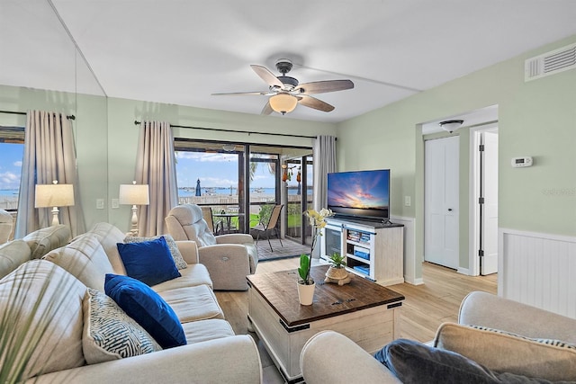 living room with light wood-style floors, visible vents, a ceiling fan, and wainscoting