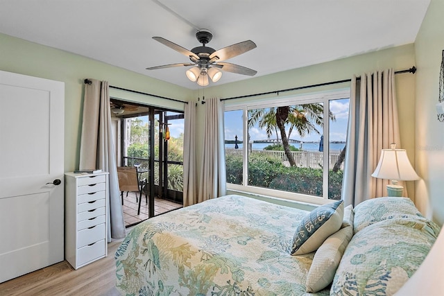 bedroom featuring a water view, light wood-style floors, access to outside, and ceiling fan