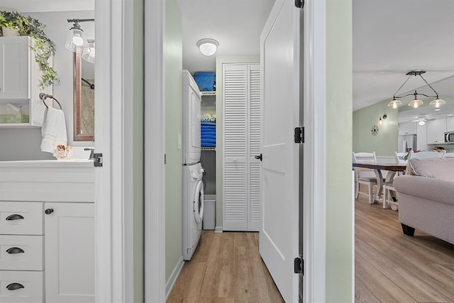 hallway featuring light wood-style flooring and stacked washer and clothes dryer