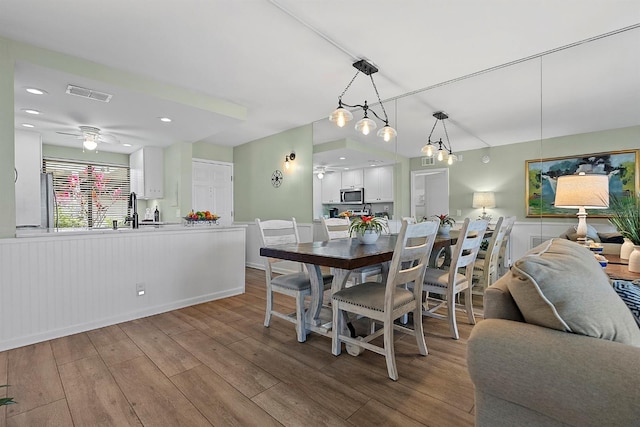 dining room featuring light wood-style floors, visible vents, and a ceiling fan