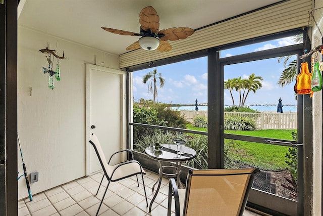 sunroom featuring a water view and a ceiling fan