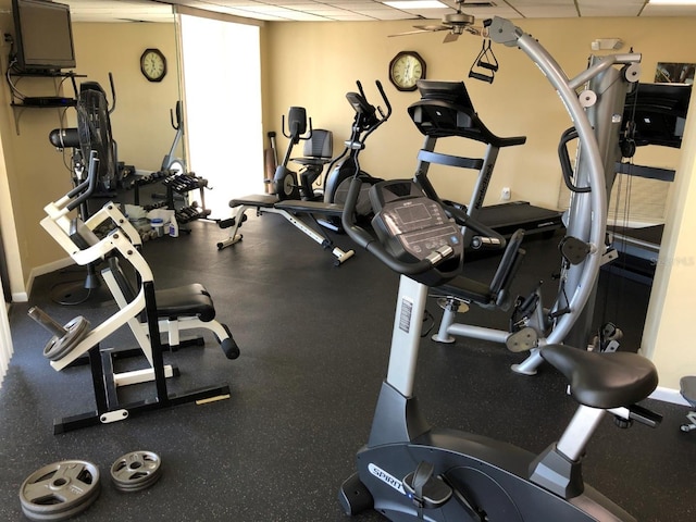 workout area with a paneled ceiling, ceiling fan, and baseboards