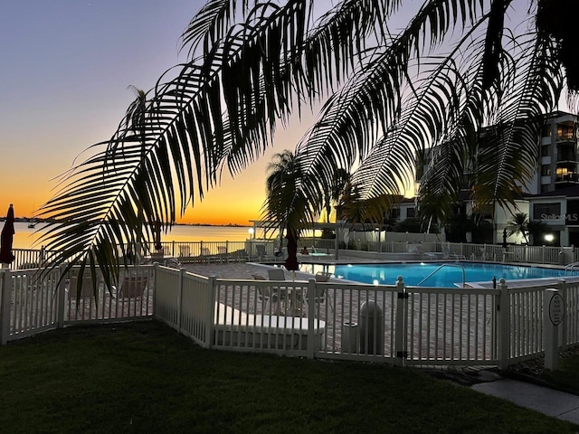 pool featuring a yard, a water view, and fence