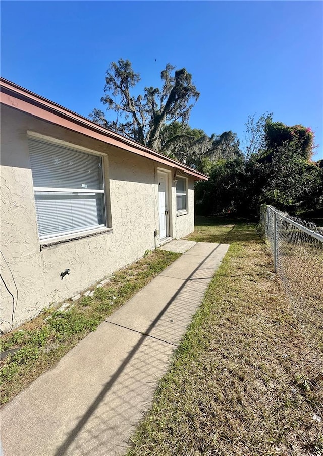 view of side of home featuring fence and stucco siding