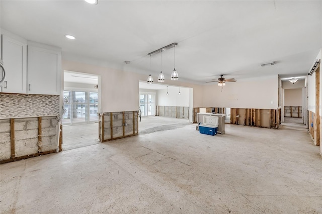 unfurnished living room featuring ceiling fan and a wood stove