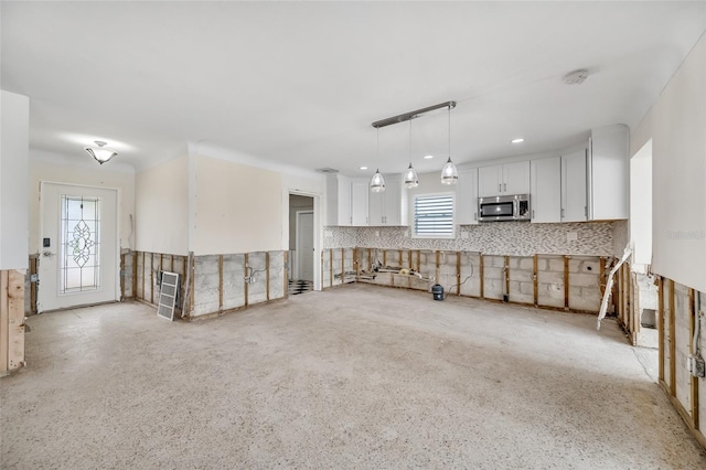 interior space with decorative light fixtures, decorative backsplash, and white cabinets