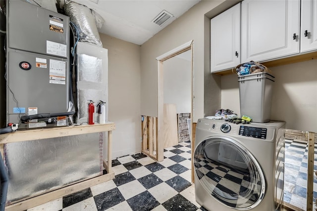 clothes washing area with washer / clothes dryer, heating unit, and cabinets