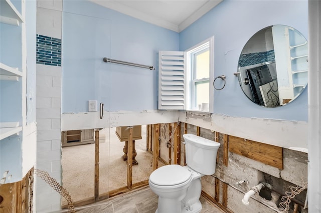 bathroom featuring crown molding, toilet, and tile walls